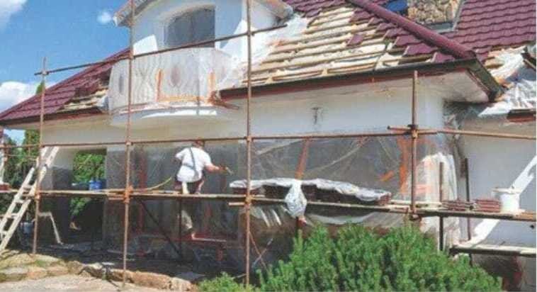 Handwerker bei Spritzarbeiten auf dem Gerüst